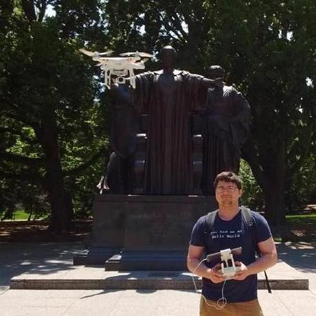 Photo of Dr. James Balamuta flying a drone next to the Alma mater